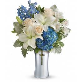 White lilies, cream roses, and blue flowers in a clear vase