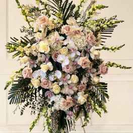 Large standing floral spray with pale roses and orchids on an easel