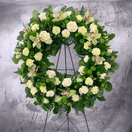 Large floral wreath with white roses, pale orchids, and green pom-pom flowers