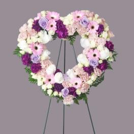 Heart-shaped floral wreath on a stand with pink, white, purple flowers