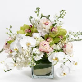 White and pale pink flowers arranged in a square glass vase