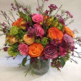 Mixed bouquet of pink, orange, and purple blooms in a clear glass vase