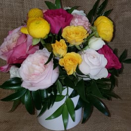 Pink, yellow, and white roses arranged in a white vase