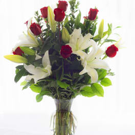 Red roses and white lilies arranged in a clear glass vase