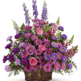 Purple and pink mixed flower arrangement in a wicker basket