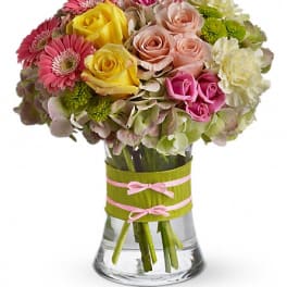 Mixed bouquet of roses, gerbera daisies, and hydrangeas in a glass vase