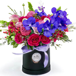 Bright mixed bouquet in a black hatbox with a lavender ribbon