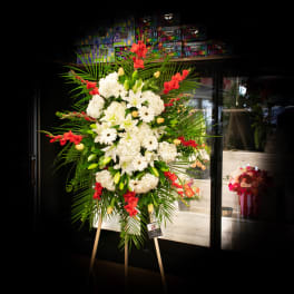 Large standing floral spray with white blooms and red accents on an easel