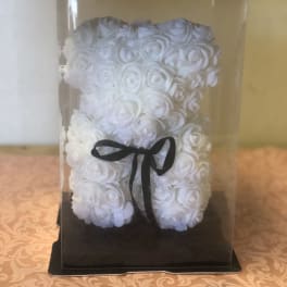 White rose teddy bear in a clear display box with a black ribbon