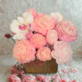 Pink floral arrangement with roses and an orchid in a square vase