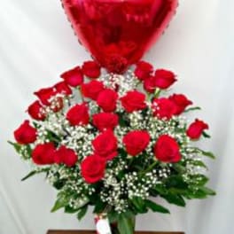 Tall vase of red roses with white baby’s breath and a red heart-shaped balloon.