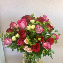 Mixed roses in pink, red, and cream arranged in a glass vase
