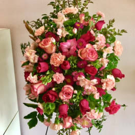 Standing floral spray with pink roses and carnations on a black easel