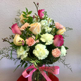 Bouquet of pink and cream roses with carnations in a glass vase