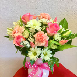 Pink and peach mixed bouquet in a white vase with a polka-dot ribbon