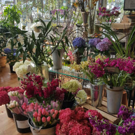 Flower shop interior with assorted pink, purple, and white flowers in metal buckets and pots