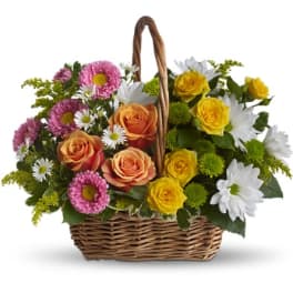 Basket of pink, yellow, and white flowers with a woven handle