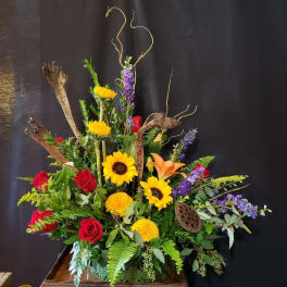 Tall floral arrangement with sunflowers, red roses, and orange lilies