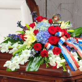 Red, white, and blue floral spray on a casket with ribbons
