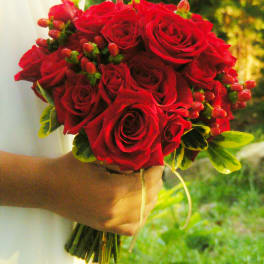 Handheld bouquet of red roses with small berry accents