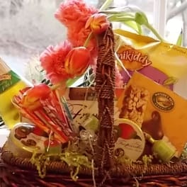 Gift basket with snacks, a bottle, and pink tulips