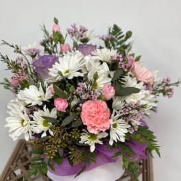 Pink and white mixed bouquet with daisies and carnations in a round box