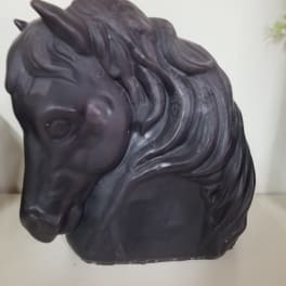 Black horse head sculpture on a white surface