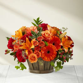 Orange and red flower arrangement in a wooden basket