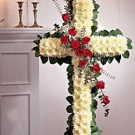 Standing cross-shaped floral arrangement of white flowers with red roses on an easel