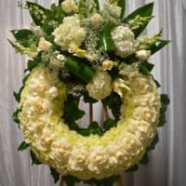White floral wreath on a stand with a matching top spray