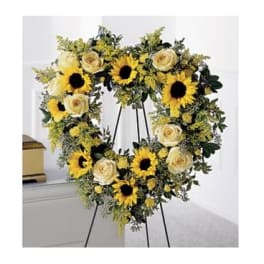 Heart-shaped floral wreath with sunflowers and cream roses on an easel