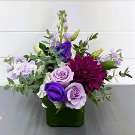 Purple and lavender flowers arranged in a green vase