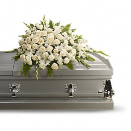 White floral casket spray on a gray coffin