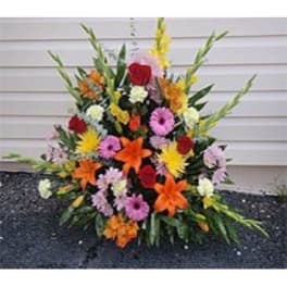 Colorful standing floral spray with lilies, roses, and daisies