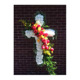 Cross-shaped floral tribute with white flowers and red, yellow, and pink roses