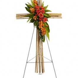Standing floral cross with orange roses and greenery on an easel