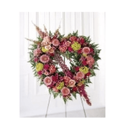 Heart-shaped floral wreath on an easel with pink and yellow blooms