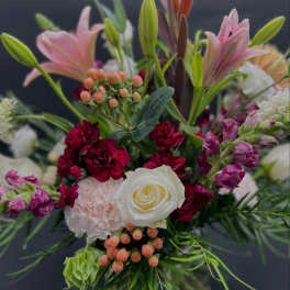 Mixed bouquet with pink lilies, white rose, and red carnations in a vase