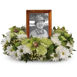 Round white and green floral wreath encircling a wooden-framed portrait.