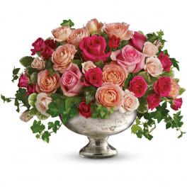 Mixed pink and peach roses arranged in a silver pedestal bowl