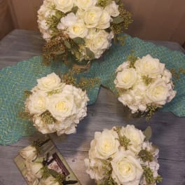 White rose bouquets with hydrangea and greenery on a table