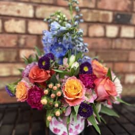 Colorful mixed flower arrangement in a pink patterned container