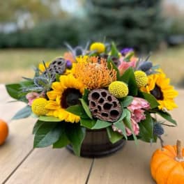 Autumn bouquet with sunflowers and orange blooms in a low container