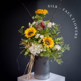 Silk sunflower arrangement in a ribbed metal vase with a bird accent