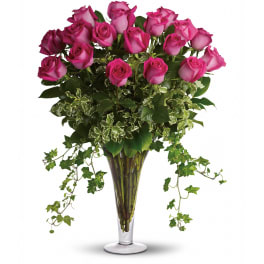 Tall arrangement of hot pink roses with abundant trailing ivy in a clear glass vase