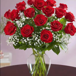 Bouquet of red roses with baby's breath in a clear glass vase