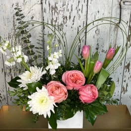 Pink tulips and roses with white chrysanthemums in a white container