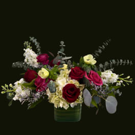 Red and pink roses with white flowers in a glass vase
