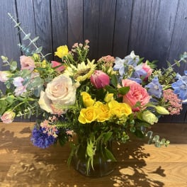 Mixed bouquet in a glass vase with roses, tulips, and blue flowers