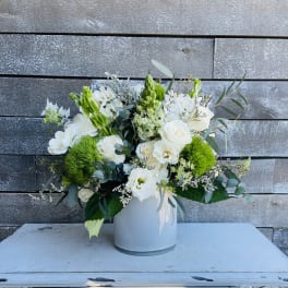 White floral arrangement in a white vase with bright green accents